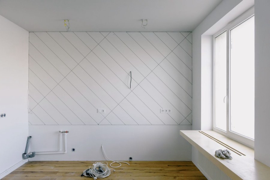 Raum im Rohbau mit vorbereiteter Wand, angezeichneten Linien und offenen Anschlüssen